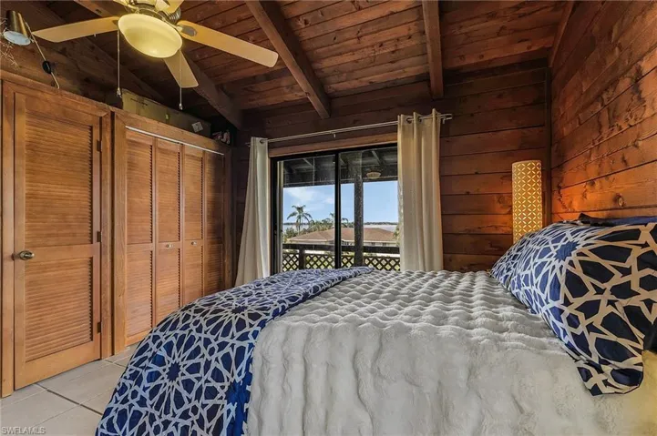 Bedroom featuring access to exterior, ceiling fan, wood walls, a closet, and light tile patterned floors