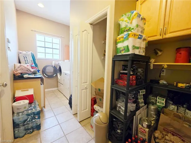 Washroom with light tile patterned floors, independent washer and dryer, and cabinet space