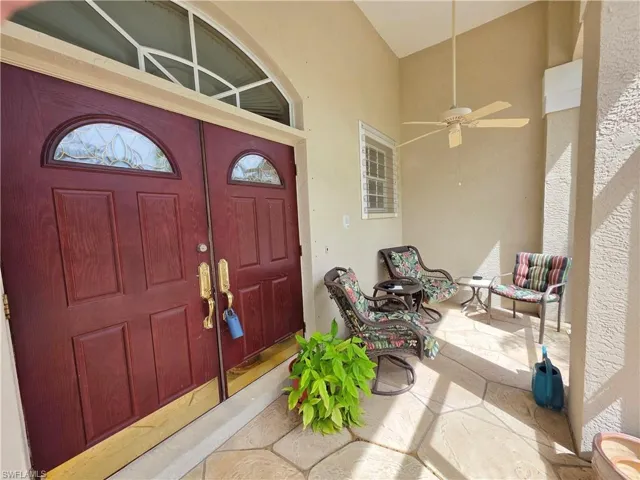 View of exterior entry with a ceiling fan, stucco siding, and a patio