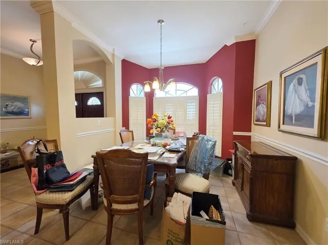 Dining space featuring light tile patterned floors, ornamental molding, and a chandelier