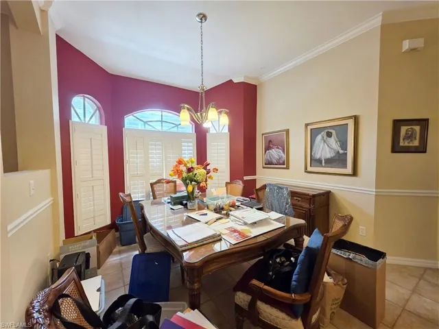 Dining room with crown molding, light tile patterned flooring, and a chandelier