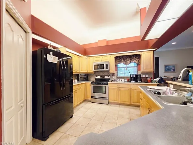 Kitchen featuring stainless steel appliances, light brown cabinets, light tile patterned flooring, tasteful backsplash, and light countertops
