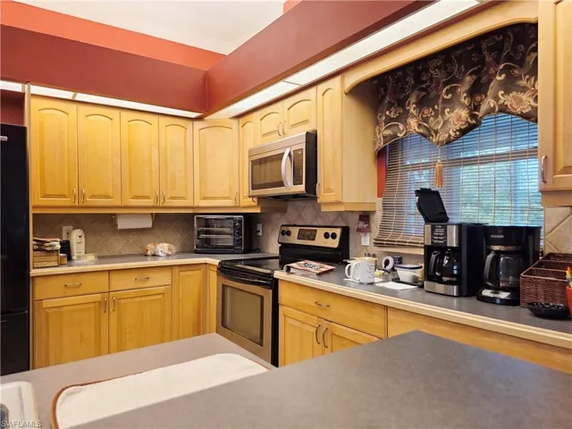 Kitchen with backsplash, stainless steel appliances, and light countertops