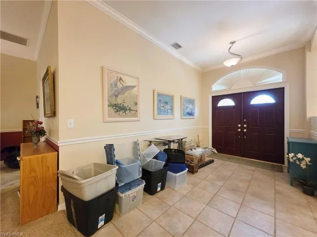 Entrance foyer featuring crown molding and light tile patterned flooring