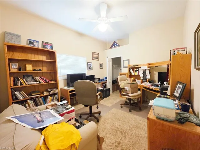 Carpeted home office with a ceiling fan