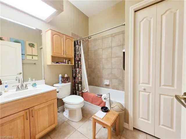 Full bathroom with shower / tub combo with curtain, vanity, and light tile patterned floors