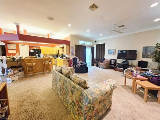 Living area featuring crown molding, light colored carpet, recessed lighting, a ceiling fan, and light tile patterned floors
