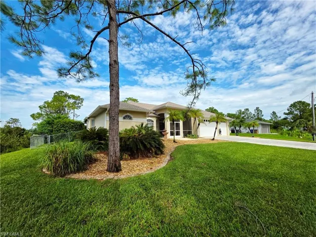 Single story home featuring concrete driveway, stucco siding, an attached garage, and a sunroom