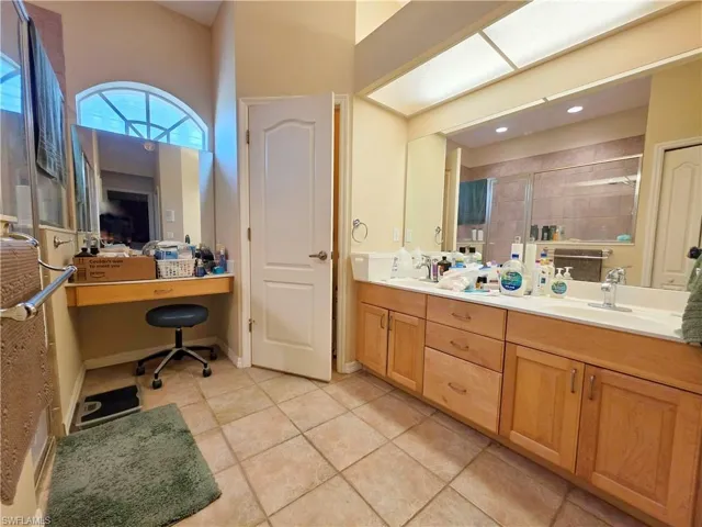 Bathroom featuring a stall shower, light tile patterned floors, and double vanity