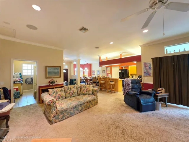 Living area featuring ornate columns, ornamental molding, light colored carpet, recessed lighting, and ceiling fan