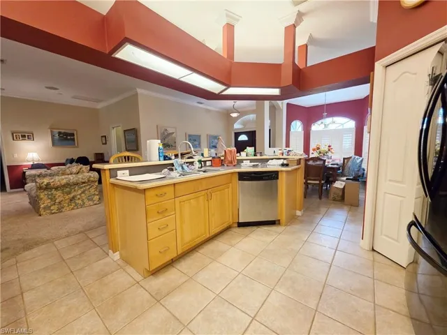 Kitchen with open floor plan, a center island with sink, light countertops, light tile patterned flooring, and dishwasher