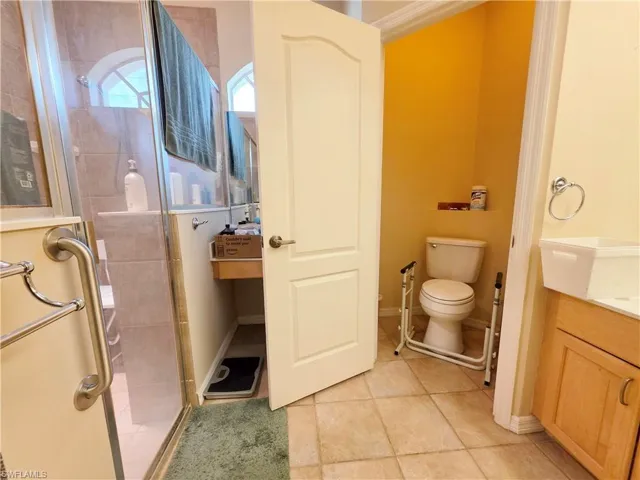 Full bath with vanity, a shower stall, and light tile patterned floors