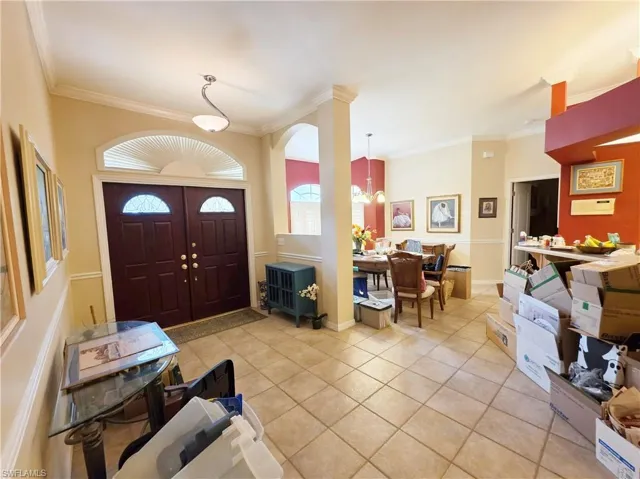 Foyer entrance featuring light tile patterned floors, crown molding, and a chandelier