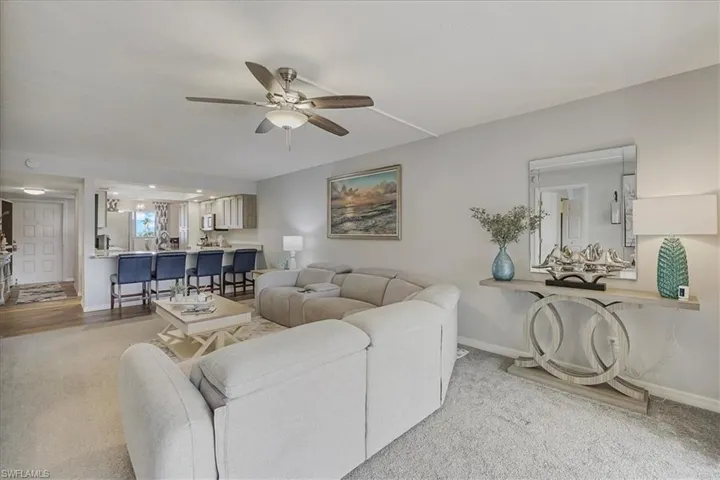 Living area with a ceiling fan and light colored carpet
