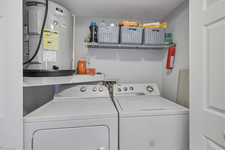 Washroom featuring water heater and washing machine and clothes dryer