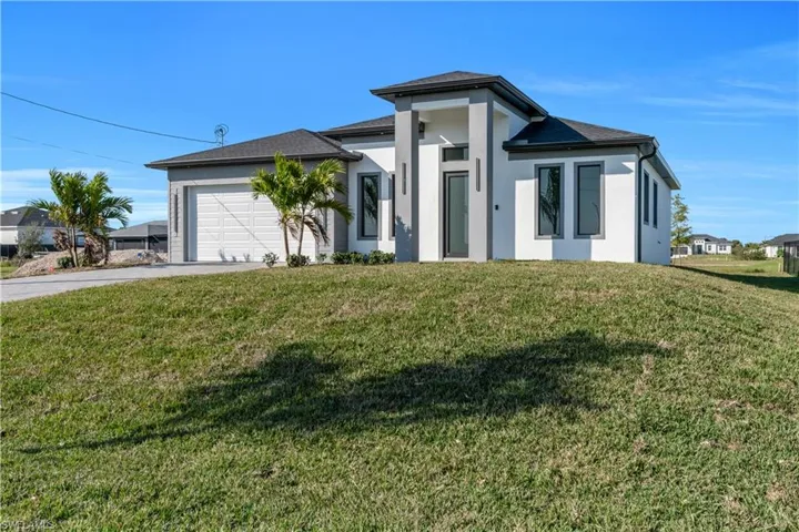 View of front of house featuring stucco siding, concrete driveway, a front lawn, and an attached garage
