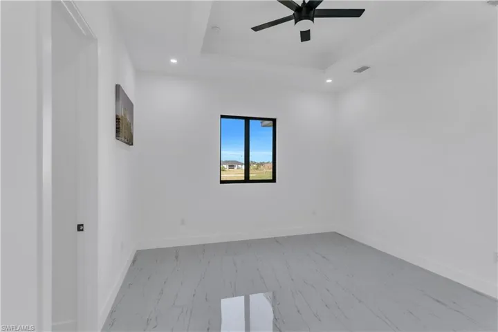 Unfurnished room with a ceiling fan, recessed lighting, light marble finish flooring, and a tray ceiling