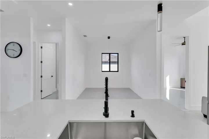 Kitchen with open floor plan, light stone countertops, and decorative light fixtures