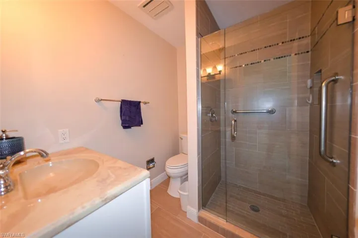Bathroom featuring an enclosed shower, toilet, and vanity