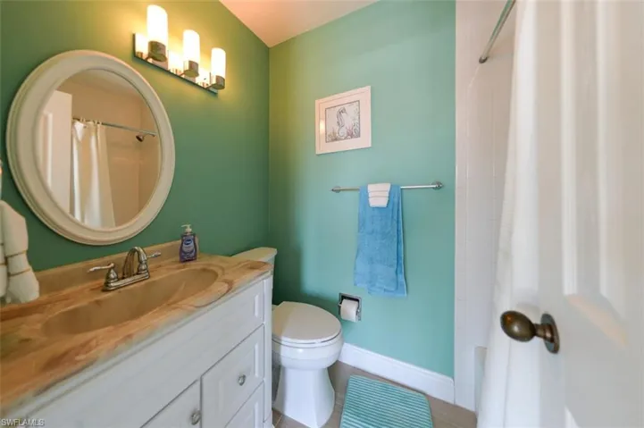 Full bathroom with tile flooring, oversized vanity, toilet, and shower / bath combination with curtain