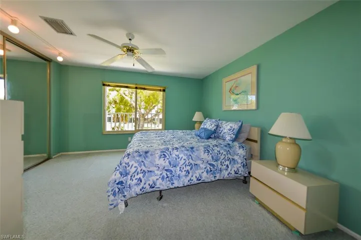 Carpeted bedroom with ceiling fan and rail lighting