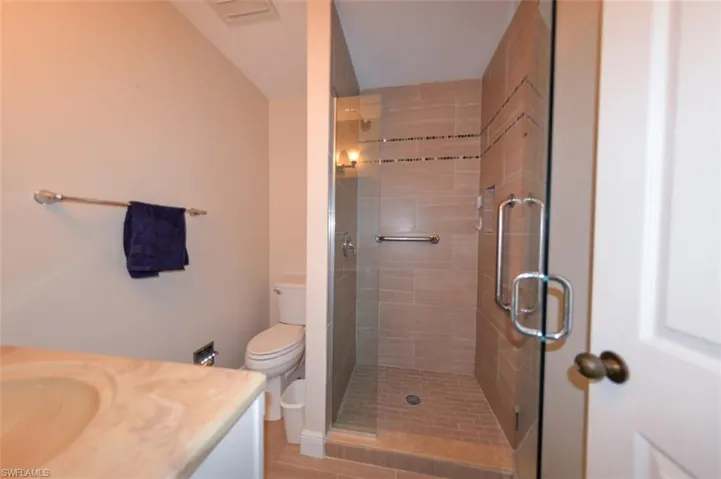 Bathroom featuring walk in shower, vanity, and toilet