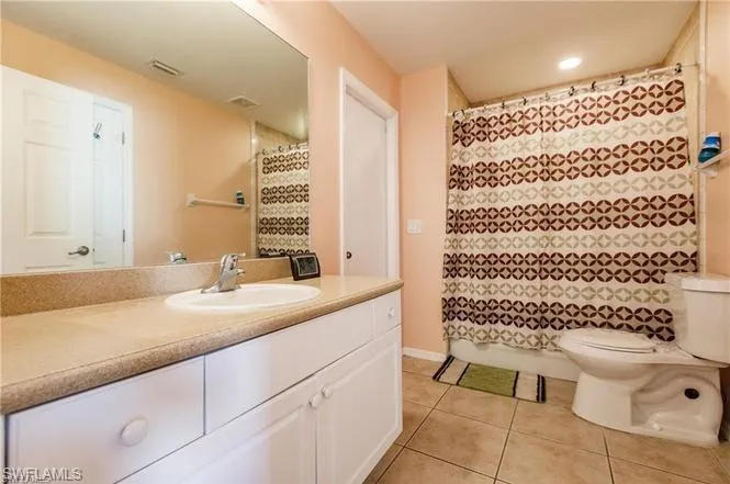 Full bath featuring vanity, light tile patterned flooring, curtained shower, and recessed lighting