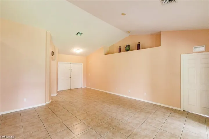Spare room with vaulted ceiling and light tile patterned flooring