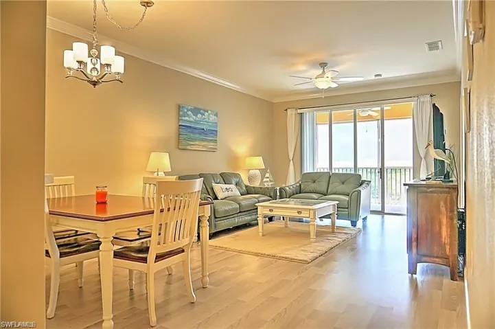 Living area featuring crown molding, light wood-style floors, ceiling fan, and a chandelier