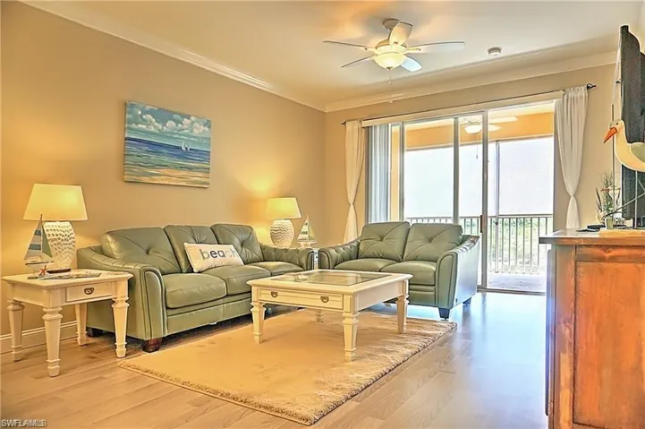 Living room featuring light wood-type flooring, crown molding, and a ceiling fan