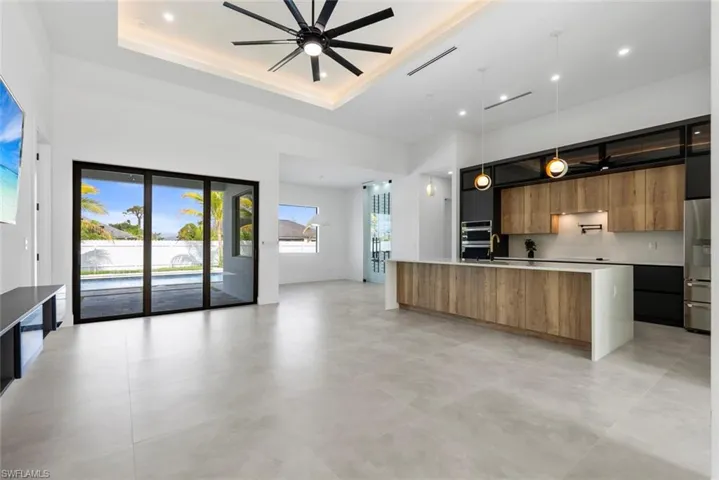 Kitchen with modern cabinets, open floor plan, a ceiling fan, a tray ceiling, and recessed lighting