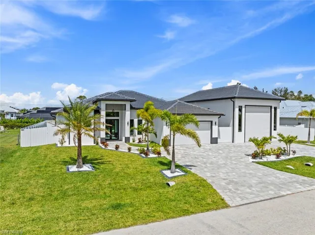 Prairie-style home with an attached garage, decorative driveway, a tile roof, and stucco siding