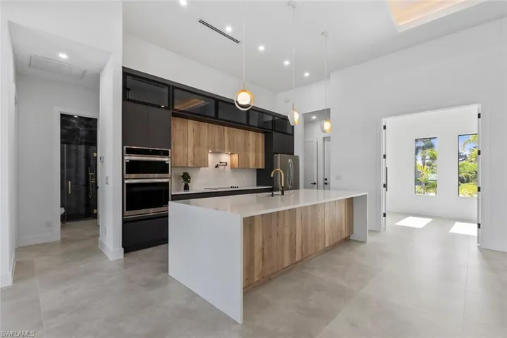 Kitchen with modern cabinets, light countertops, appliances with stainless steel finishes, a sink, and a large island with sink