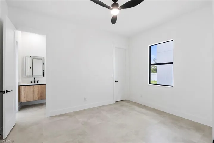 Unfurnished bedroom with baseboards, a sink, ensuite bath, and a ceiling fan