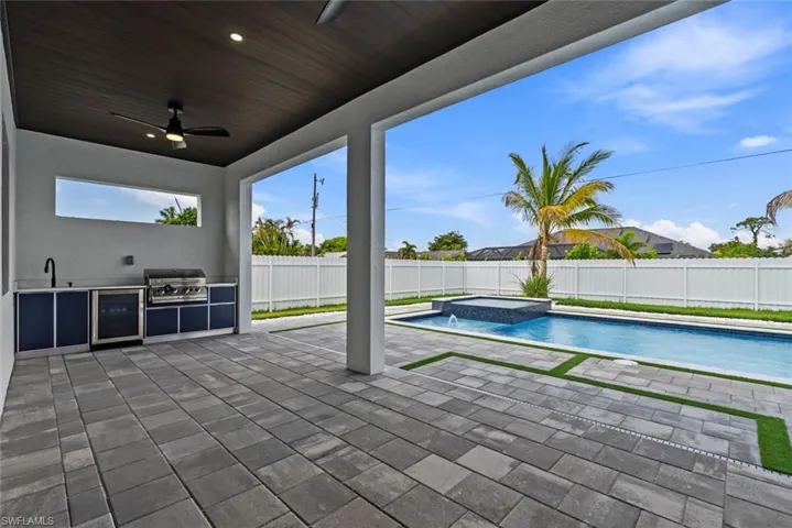 View of swimming pool with exterior kitchen, a grill, a fenced backyard, ceiling fan, and a patio area
