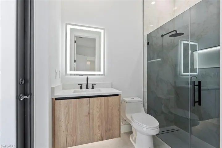 Bathroom with toilet, a stall shower, vanity, and tile patterned flooring