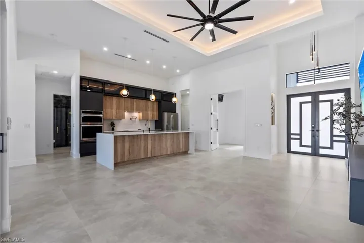Kitchen featuring modern cabinets, a towering ceiling, stainless steel appliances, open floor plan, and a tray ceiling