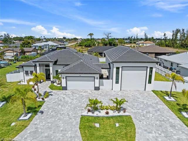 View of front of house featuring a garage, a residential view, decorative driveway, a tiled roof, and stucco siding