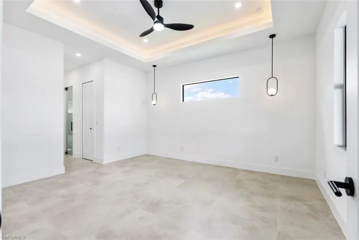 Unfurnished room featuring a ceiling fan, a tray ceiling, recessed lighting, baseboards, and concrete floors