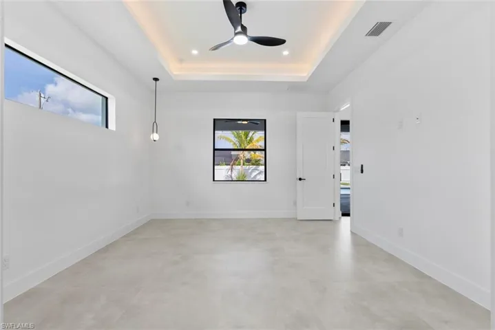 Unfurnished room featuring a ceiling fan, plenty of natural light, a tray ceiling, recessed lighting, and finished concrete floors