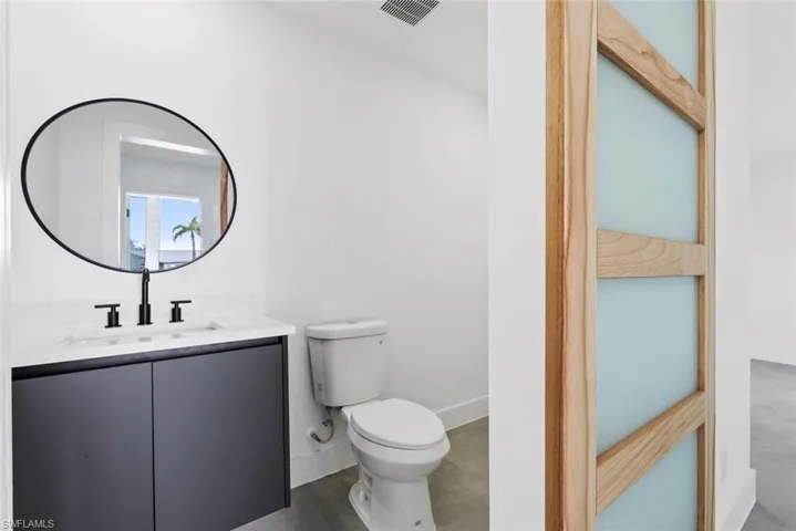Half bathroom featuring toilet, vanity, and baseboards