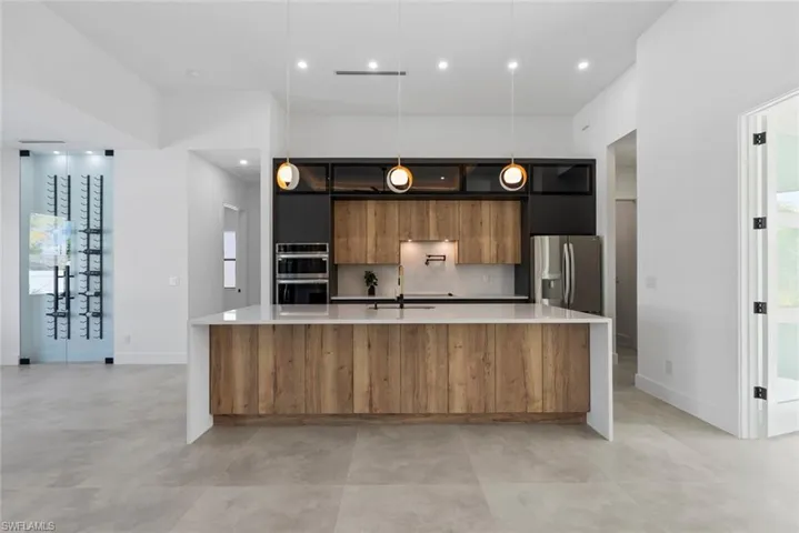 Kitchen featuring modern cabinets, stainless steel appliances, light countertops, a sink, and baseboards
