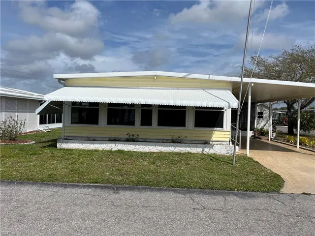 View of front of property with a carport and a front lawn