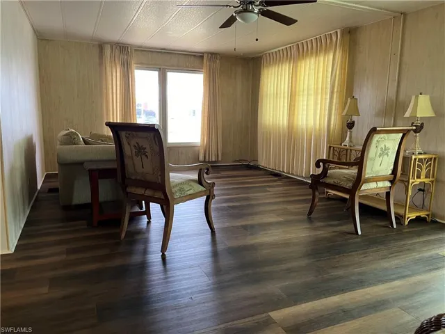 Sitting room featuring wood walls, dark hardwood / wood-style flooring, and ceiling fan
