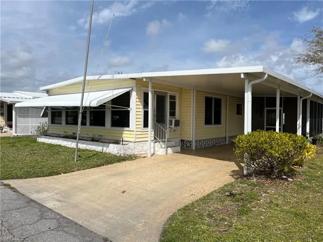 Manufactured / mobile home with cooling unit, a front lawn, and a carport