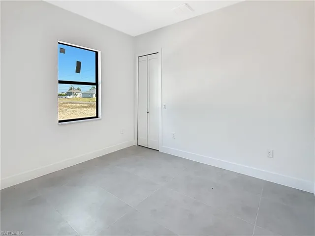 Room featuring light gray walls, white baseboards, and light gray tile flooring