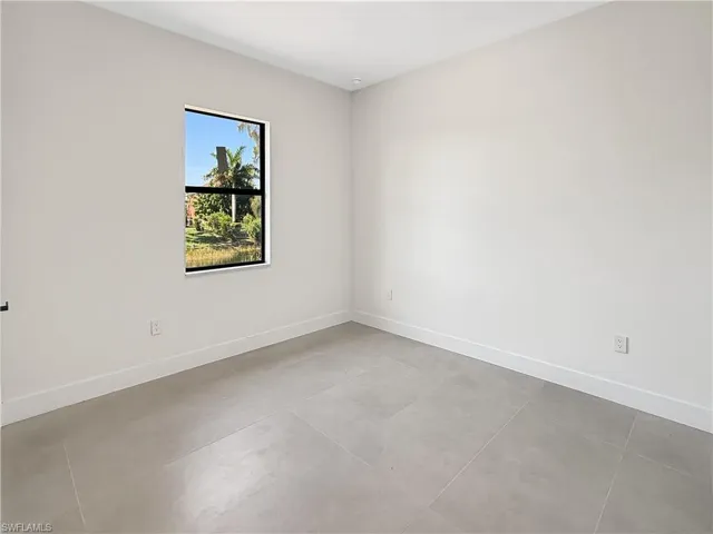 Neutral-toned interior room featuring light gray walls, white baseboards, and large format square floor tiles