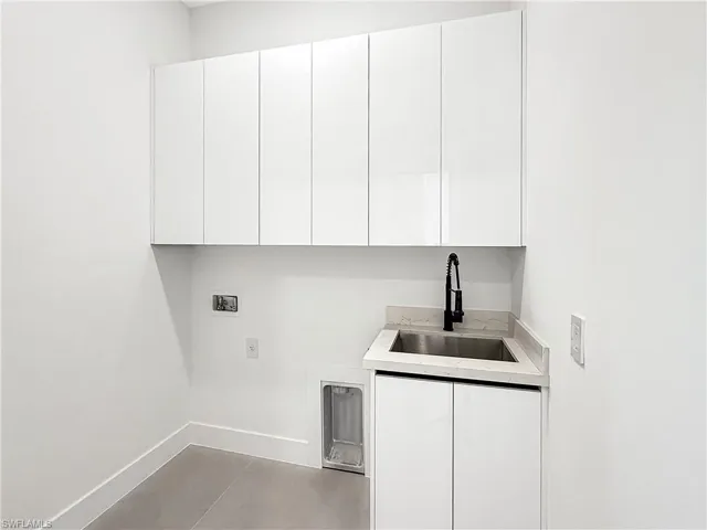 Modern laundry area featuring white flat-panel cabinetry and a stainless steel utility sink