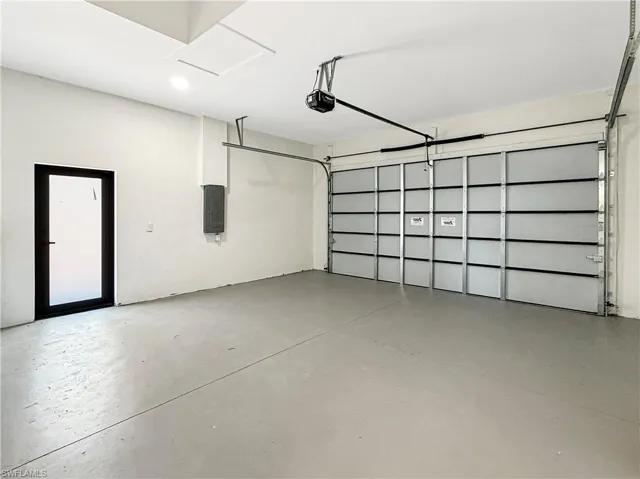 Spacious garage featuring a large sectional overhead door and a separate entry door
