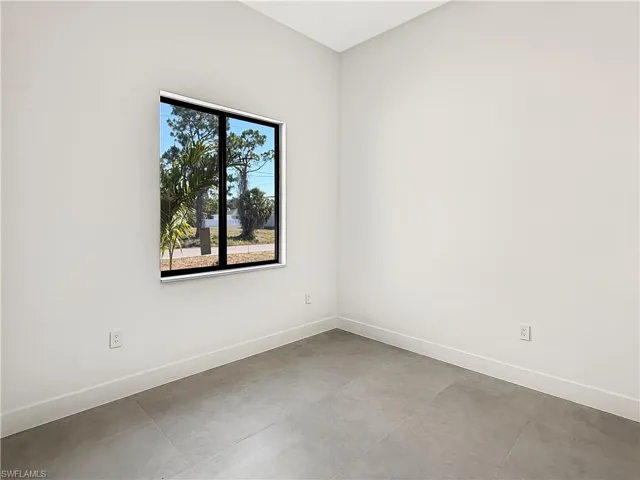 Modern interior space featuring light gray walls, a contemporary window with black trim, and gray tile flooring